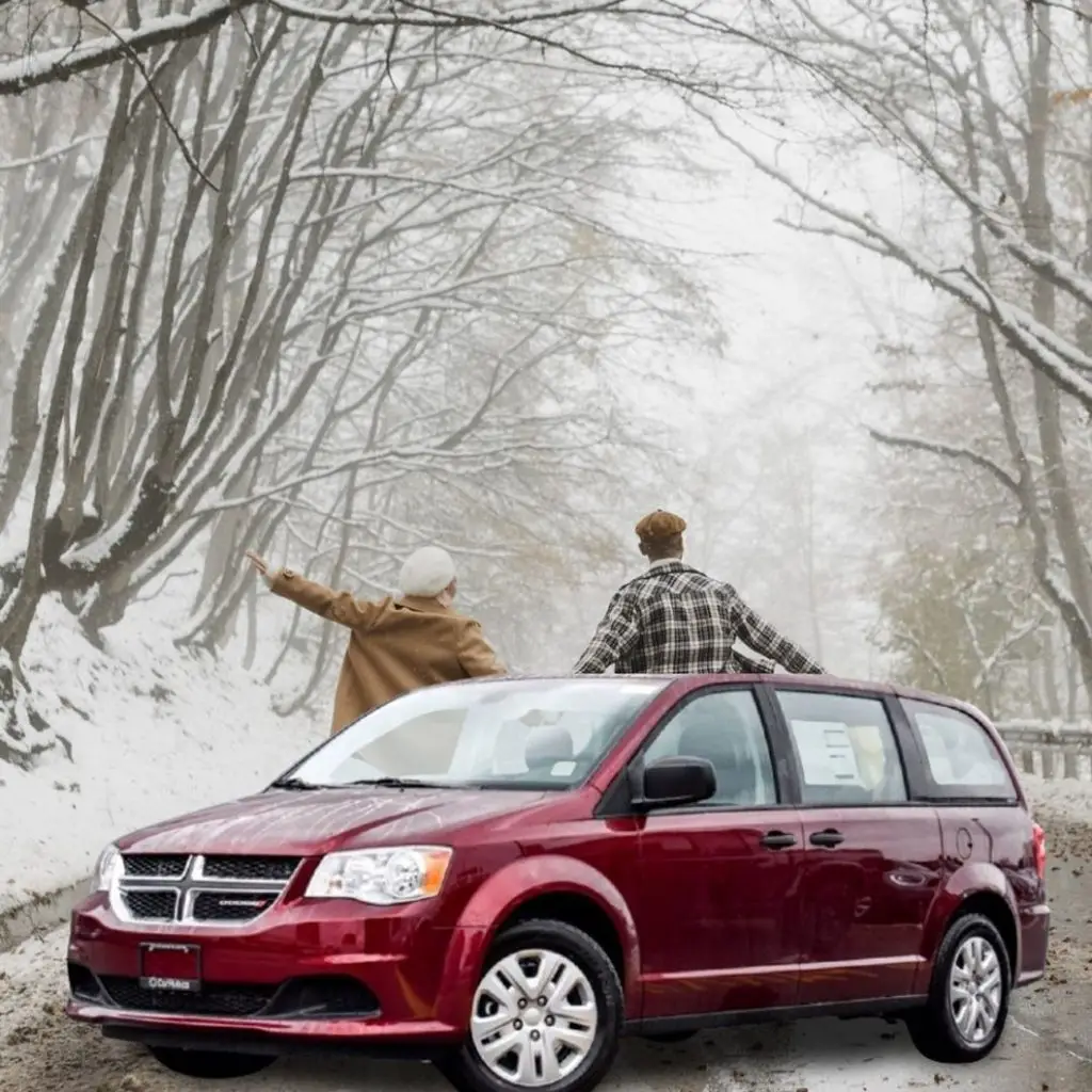 Couple standing through sunroof of red Dodge Grand Caravan on snowy forest road