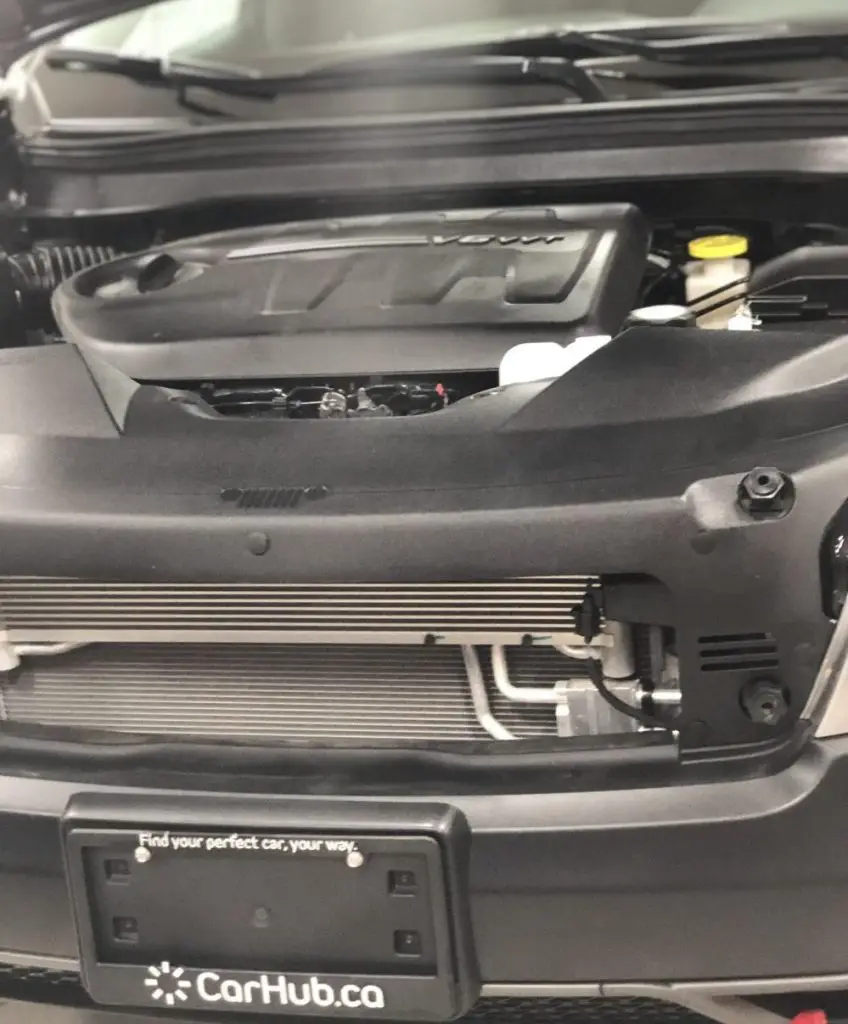 Car engine bay close-up with CarHub.ca license plate frame reading "Find your perfect car, your way"