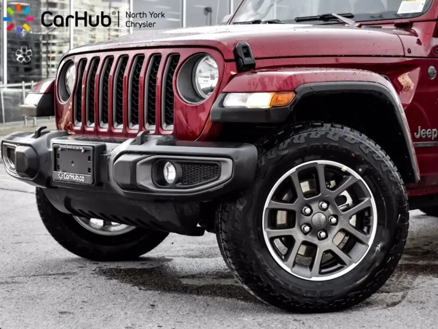 Close-up of red Jeep Wrangler front wheel, grille, and off-road tire at CarHub North York Chrysler