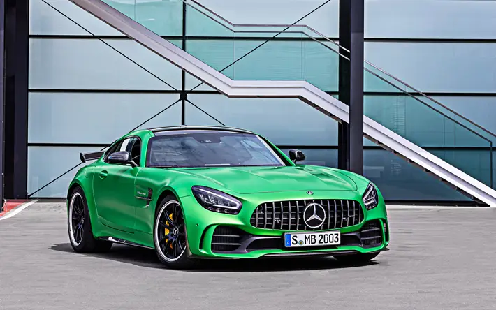 Green Mercedes-AMG GT R sports coupe parked outside modern glass building