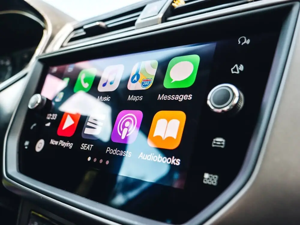 Car infotainment touchscreen displaying Apple CarPlay apps including Music, Maps, and Messages