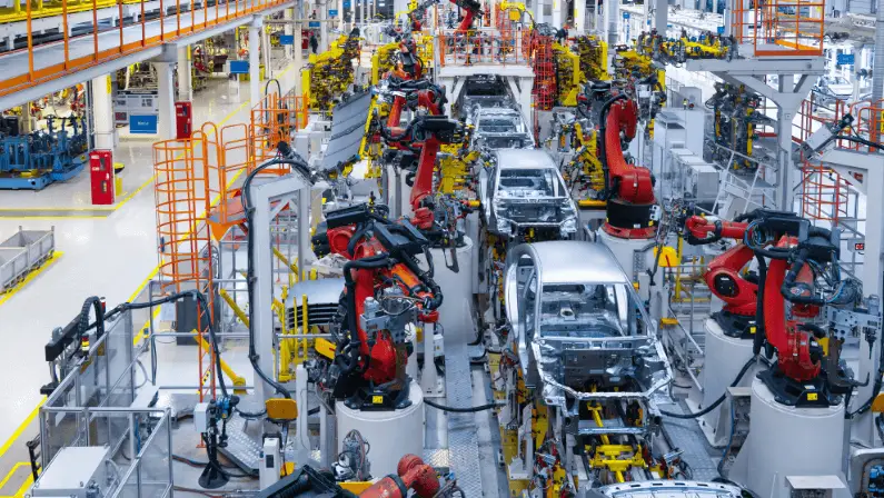 Automated car assembly line with robotic arms welding vehicle frames in a modern automobile manufacturing plant