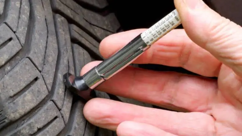 Checking tire tread depth using a tire tread depth gauge
