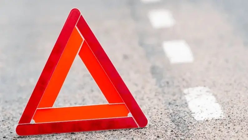 Red hazard warning triangle sign placed on road pavement after breakdown or accident