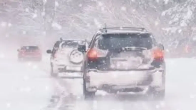 Rear view of cars driving in heavy snowfall on slippery winter road