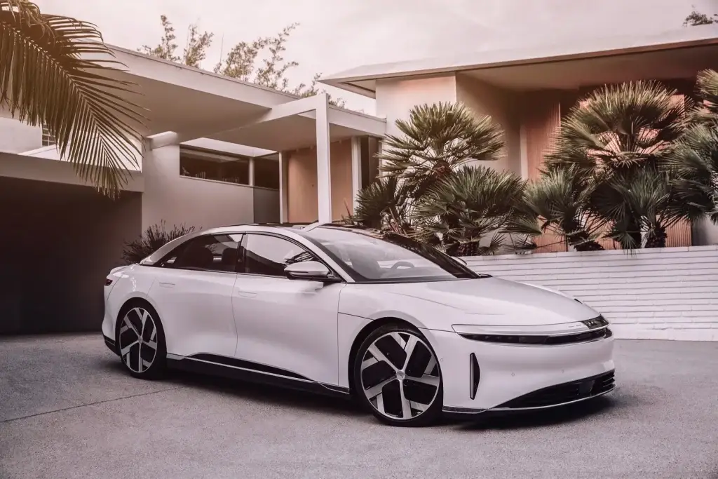White Lucid Air electric sedan parked in driveway of modern desert home
