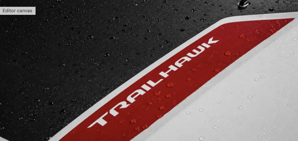 Close-up of red and white Jeep Trailhawk badge on rain-covered black vehicle exterior